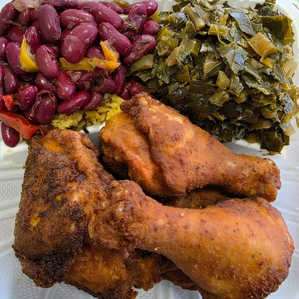 Village BBQ meal with fried chicken, red beans and rice, and collard greens.